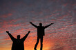 © Carolyn Lagattuta/Stocksy - Two men rejoicing in front of a vibrant sky