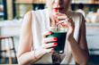© Lumina/Stocksy - Woman Drinking a Green Smoothie at a Cafe