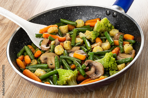 Fotografía White spoon in frying pan with fried vegetable mix