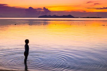 Child playing on ocean beach. Kid at sunset sea.