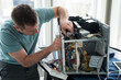 © blurMEDIA/Stocksy - Man Fixing Broken Microwave Oven Appliance In Kitchen