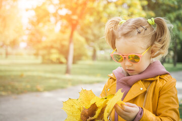 Little three-year-old girl playing with feathery leaves