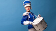 © Ulia Koltyrina - Charming cheerful drummer in a blue uniform, sings and plays the drum.