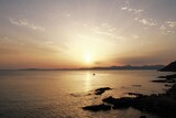 Fototapeta Niebo - Atardecer en el mar con barco y sol naranja entre las nubes