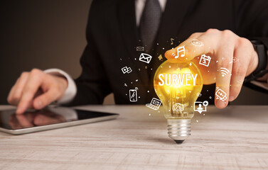 Businessman holding light bulb with SURVEY inscription, social media concept