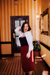 A girl in a white blouse black T-shirt and skirt stands in the beautiful corridor of the restaurant hotel. wallpaper classics in stripe yellow