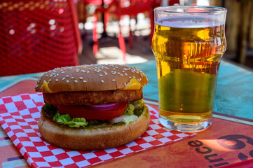 Poster - Fast food in bar served outdoor in sunny day, vegetarian hamburber and glass of cold beer