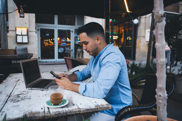 Thoughtful ethnic man typing on smartphone