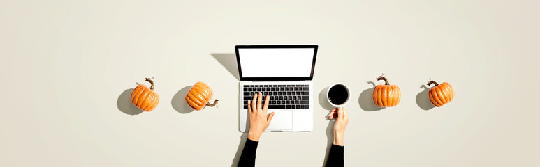 Autumn pumpkins with person using a laptop computer from above