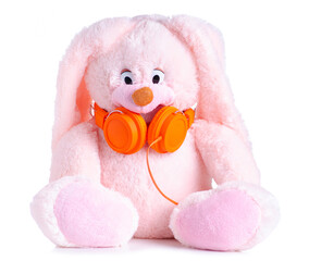 Wall Mural - Pink bunny soft toy with orange headphones on white background isolation