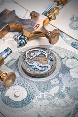 The mechanism of an old clock and an old tool lie on an engraving of a mechanism with gears.