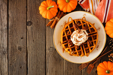Poster - Pumpkin spice waffle with whipped topping, caramel and pecans. Above view table scene on a dark wood background with copy space. Autumn breakfast concept.