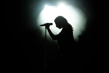 Black Silhouette Of Female Singer With White Spotlights In The Background