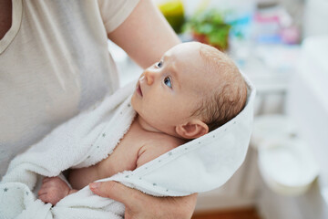 mother holding baby wrapped in towel after bath
