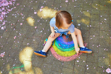 Wall Mural - toddler girl drawing rainbow with colorful chalks