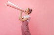 © Look! - Girl in overalls shouts into horn and looks into camera on pink background