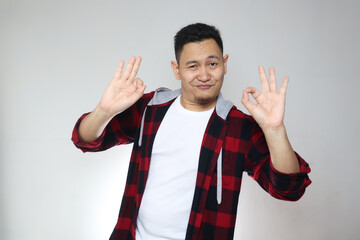 Wall Mural - Young Asian man samiling at camera and shows okay OK sign. Close up body portrait against white