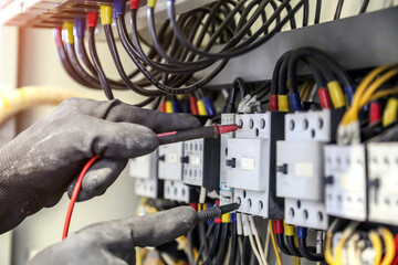 Wall Mural - Electrical engineer using measuring equipment to checking electric current voltage at circuit breaker and cable wiring system for maintenance in main power distribution board.