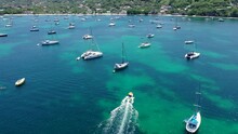 Aerial, Pov, A Small Motor Boat Among Anchored Sailboats Off The Coast Of An Island, Grenada