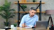 © viacheslav - Man in home office wears wireless earphones talks uses laptop computer, search information in notebook. Businessman makes remote online video call conference webcam meeting chat with company employees