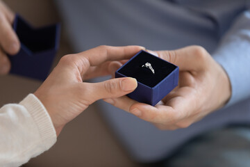 Will you marry me. Close up of young male hand holding gift box with engagement ring presenting it to beloved female making love confession and proposal of marriage, betrothal of loving couple concept