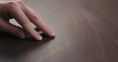 Canvas Print - Slow motion of man hand checking toned walnut table surface with oil finish