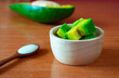 Avocado slices in a wooden cup placed on a brown wood surface are free radicals. And beneficial to the body