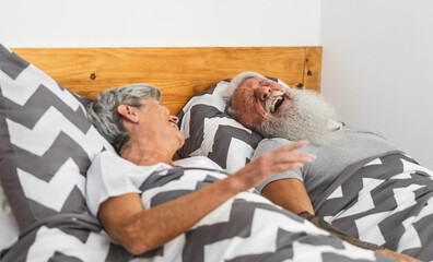 Happy senior couple in bed - Hipster mature people having funny bed time together - Elderly lifestyle and love relationship concept