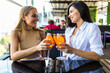 © F8  \ Suport Ukraine - Young women drinking aperol spritz, clink glasses with friends, looking at camera in modern cafe