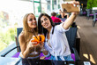© F8  \ Suport Ukraine - Two attractive young woman take a selfie while sitting and chilling in the summer terrace of city cafe