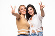 © F8  \ Suport Ukraine - Two playful girls standing together and showing peace gestures while looking at the camera over white background