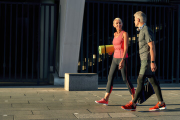 Wall Mural - Full of energy. Side view of active middle-aged couple in sports clothing going to exercise together outdoors