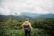 © Kateryna - Young stylish guy photographer with a backpack and a camera stands enjoying and is inspired by the amazing mountain landscape