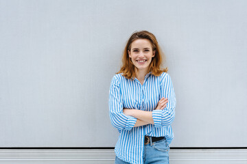 Wall Mural - Happy friendly woman standing with folded arms