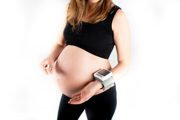 Wall Mural - Pregnant woman measures her blood pressure with wrist tonometer heart rate level.