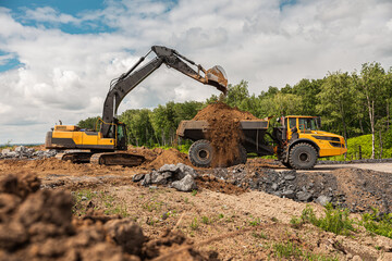 Large quarry dump truck. Big yellow mining truck at work site. Loading coal into body truck. Production useful minerals. Mining truck mining machinery to transport coal from open-pit production