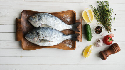 Two rainbow trout on a board, with herbs , ready for cooking.