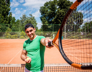 Portrait of young athletic man on tennis court.