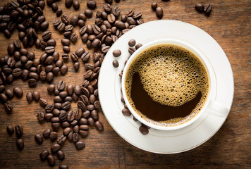 cup of coffee with beans on wooden table