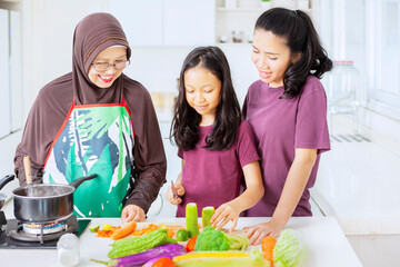 Wall Mural - Cute little girl learning cut vegetables in kitchen