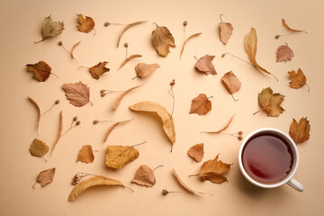 Naklejka na meble Flat lay composition with cup of hot drink and autumn leaves on beige background. Cozy atmosphere