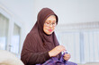 © Creativa Images - Old Muslim woman using a needle to sewing a cloth