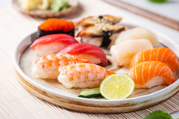 Wall Mural - Set of sushi and maki on plate with soy sauce and chopsticks on white background. Top view with copy space