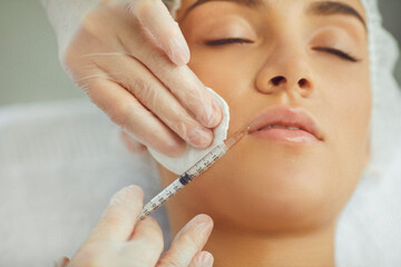 Wall Mural - Therapists hands injecting filler botox for correction upper lip of young woman