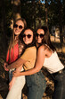 Three beautiful young women in sunglasses are smiling hugging in the field on a sunny afternoon. Happy girls in the field in summer