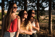 Three beautiful and young women in sunglasses stand in the field and smiling on a sunny day. Happy girls in the field in summer