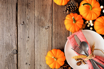 Poster - Thanksgiving table setting with cutlery on a plate with napkin and pumpkin border against a rustic wood background. Copy space.