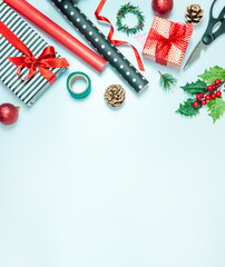 Gift boxes wrapped in black and white striped and red paper with wrapping materials over a blue background. Christmas presents preparation. Copy space.