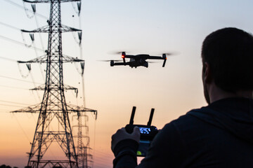 Wall Mural - man operating drone close to the electrical wire/ man holding remote control drones / drone controll