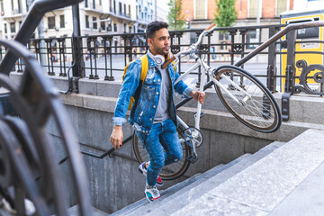 Latino Young Man Carrying Bike Going Upstairs From Underground . Transport Concept.